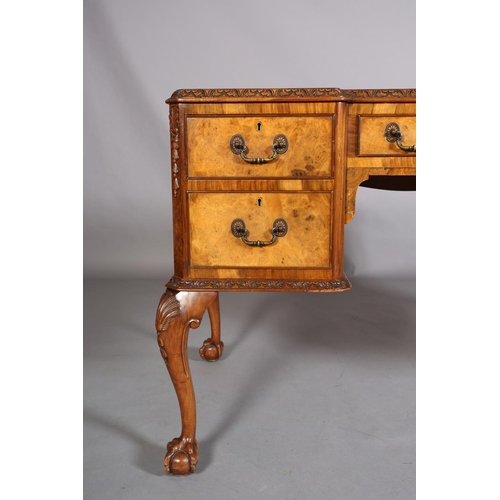 385 - AN 18TH CENTURY-STYLE FIGURED WALNUT DESK, inverted breakfront, having three incised leather panels,... 