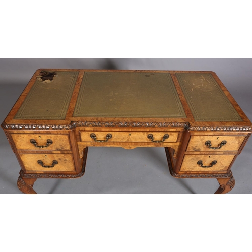 385 - AN 18TH CENTURY-STYLE FIGURED WALNUT DESK, inverted breakfront, having three incised leather panels,... 