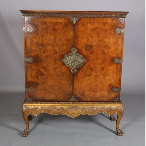 386 - A FIGURED WALNUT CROSSBANDED AND PARCEL GILT DRINKS CABINET, having a moulded cornice and demi-lune ... 