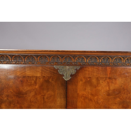 386 - A FIGURED WALNUT CROSSBANDED AND PARCEL GILT DRINKS CABINET, having a moulded cornice and demi-lune ... 