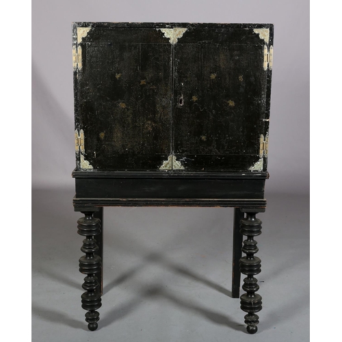 413 - AN EBONISED DECOUPAGE CABINET ON STAND, having two doors, the interior fitted with an arrangement of... 