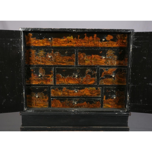 413 - AN EBONISED DECOUPAGE CABINET ON STAND, having two doors, the interior fitted with an arrangement of... 