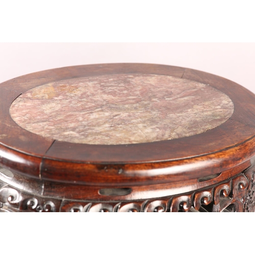 114 - A 19TH CENTURY CHINESE HARDWOOD AND MARBLE INSET URN STAND OF OVAL OUTLINE, the apron pierced and ca... 