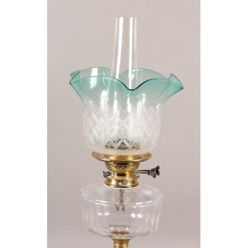 40B - A VICTORIAN BRASS OIL LAMP, having an etched and turquoise frilled shade, with a glass reservoir on ... 