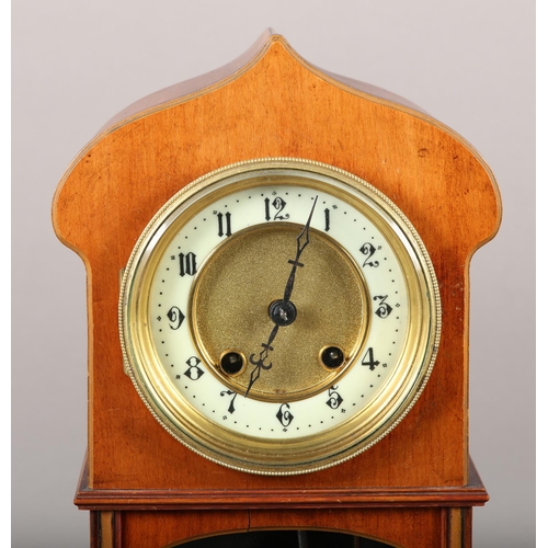 50 - AN ART NOUVEAU MAHOGANY AND GLAZED MANTEL CLOCK of arched outline, having a two part dial, black Ara... 