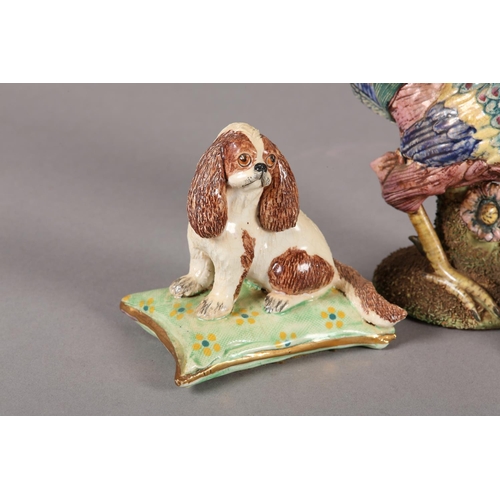 82 - A BASIL MATTHEW POTTERY MODEL OF A SPANIEL, sitting on a green and gilt cushion, 8cm high and anothe... 