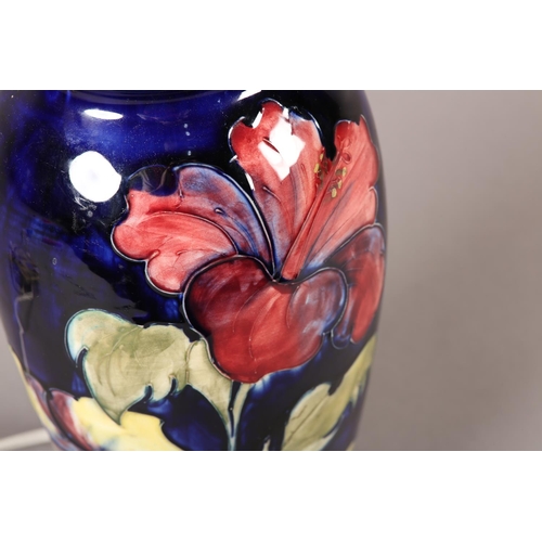 91 - A MOORCROFT LAMP, of baluster form, painted with yellow and purple hibiscus blooms and foliage, 35cm... 