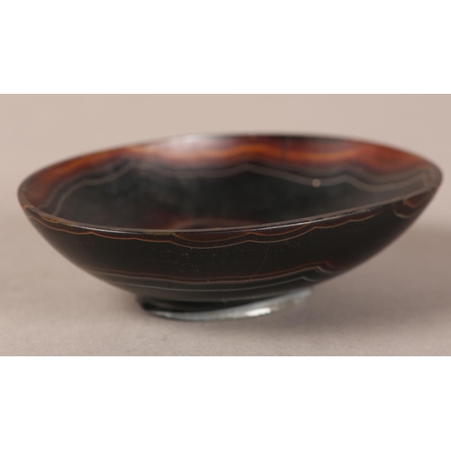 18 - A banded agate bowl of oval outline on foot rim, 9cm wide x 6.5cm deep x 2.75cm high (two cracks to ... 