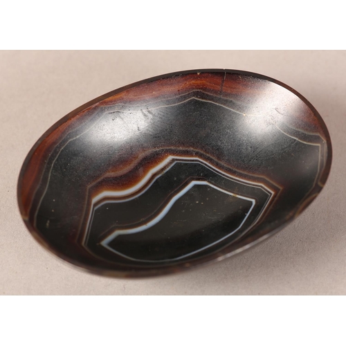 18 - A banded agate bowl of oval outline on foot rim, 9cm wide x 6.5cm deep x 2.75cm high (two cracks to ... 