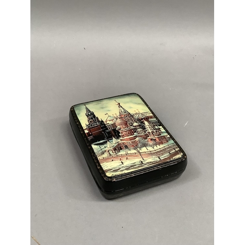 17 - A modern Russian lacquered hinged box, the lid hand painted with a winters scene of St Basil's cathe... 