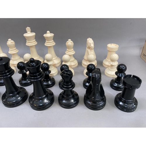 114 - A outdoors chess set in cream and black plastic, the king measuring 21cm high