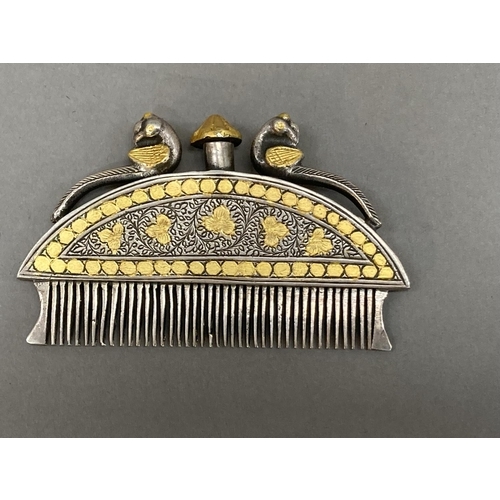 8 - An Indian, white metal moustache comb with gilt metal inlay, the finial, surmounted by two peacocks,... 