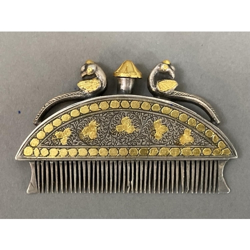 8 - An Indian, white metal moustache comb with gilt metal inlay, the finial, surmounted by two peacocks,... 