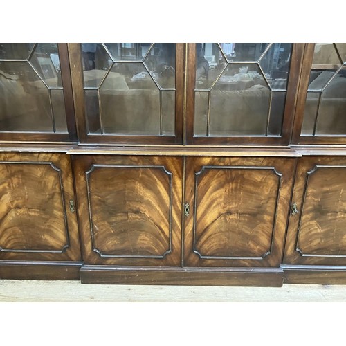 440 - A mahogany breakfront bookcase having a  moulded and dentil cornice above four tracery glazed doors,... 