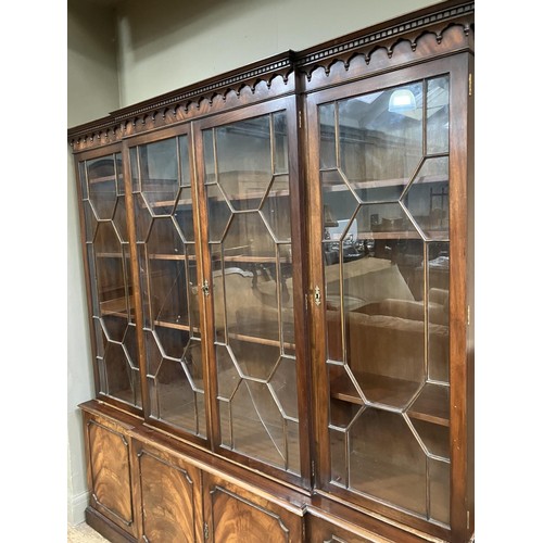 440 - A mahogany breakfront bookcase having a  moulded and dentil cornice above four tracery glazed doors,... 