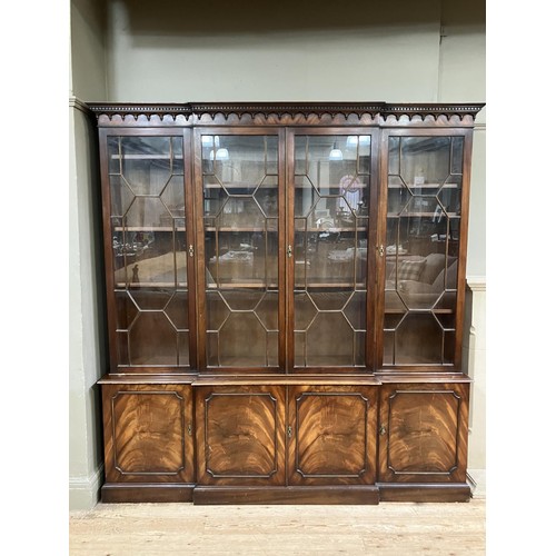 440 - A mahogany breakfront bookcase having a  moulded and dentil cornice above four tracery glazed doors,... 