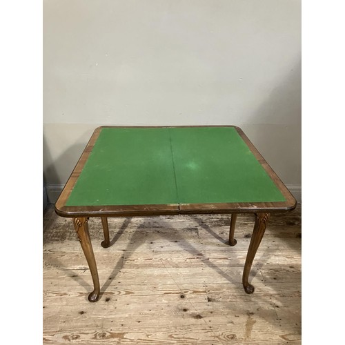 448 - An 18th century style walnut fold over card table with shaped apron and on slender cabriole legs car... 