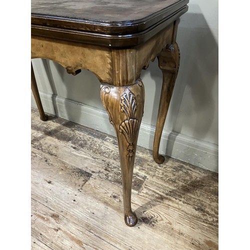 448 - An 18th century style walnut fold over card table with shaped apron and on slender cabriole legs car... 