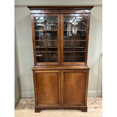 452 - A 19th century mahogany book case cupboard having a moulded cornice above two tracery glazed doors a... 