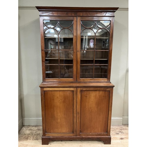 452 - A 19th century mahogany book case cupboard having a moulded cornice above two tracery glazed doors a... 