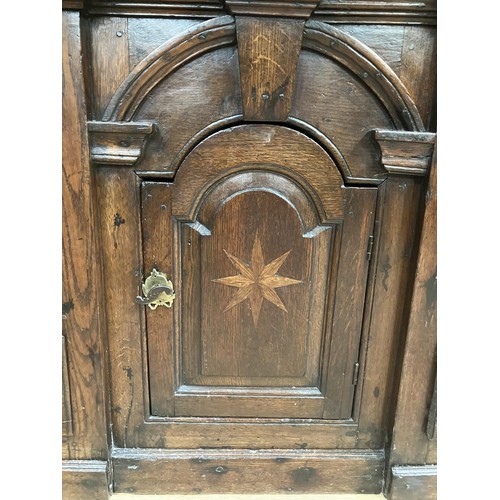 458 - A oak dresser base having an inverted breakfront arched door cupboard inlaid with star paterae to th... 