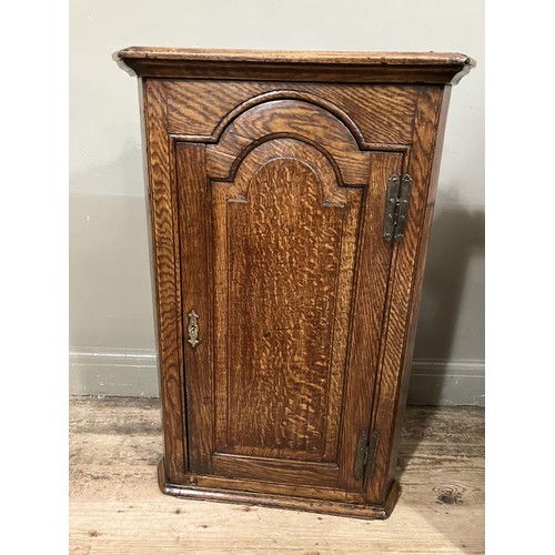 460 - A 19th century oak corner hanging cupboard having  moulded cornice above semi arched panel door and ... 