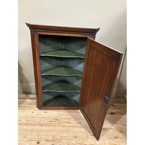 463 - A 19th century oak corner hanging cupboard with moulded and dentil cornice above an indented panel d... 