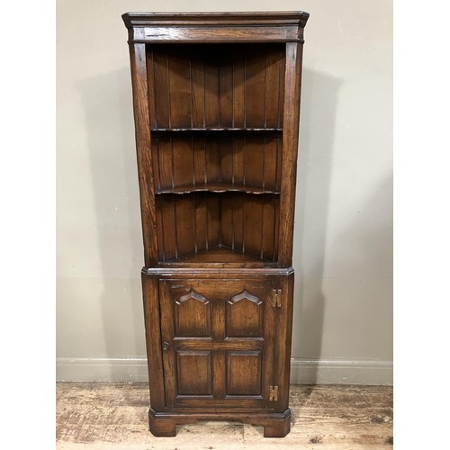 471 - An oak standing corner cupboard having a moulded cornice above two open shaped shelves, the lower se... 