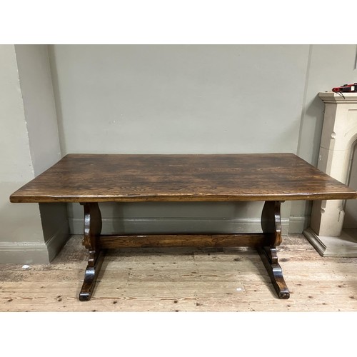 495 - An oak refectory dining table on shaped standards joined by stretcher, 183cm x 90cm