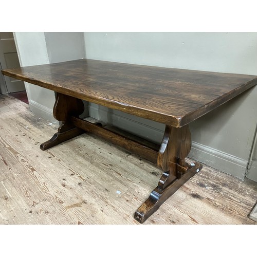 495 - An oak refectory dining table on shaped standards joined by stretcher, 183cm x 90cm