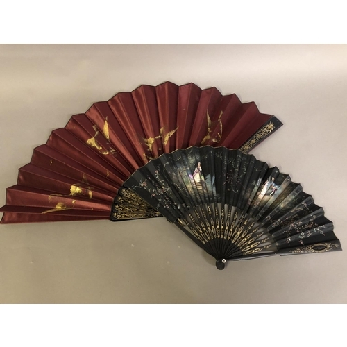 35 - A black wood fan, carved and gilded, early 20th c, mounted with a silk leaf, painted with a courting... 