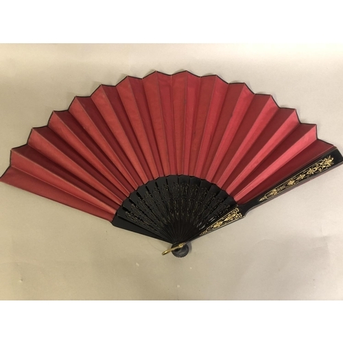 35 - A black wood fan, carved and gilded, early 20th c, mounted with a silk leaf, painted with a courting... 