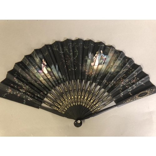 35 - A black wood fan, carved and gilded, early 20th c, mounted with a silk leaf, painted with a courting... 