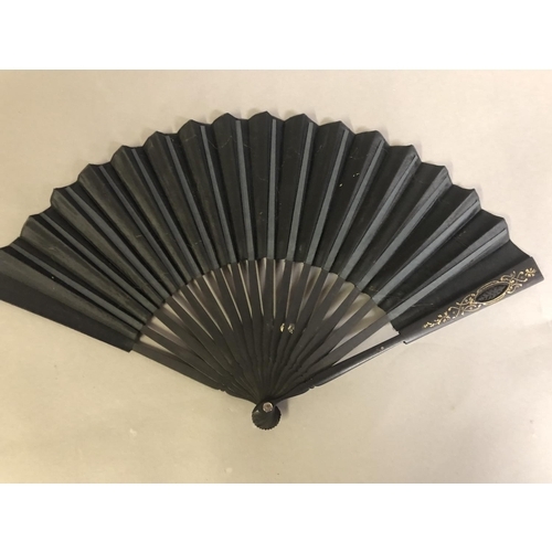 35 - A black wood fan, carved and gilded, early 20th c, mounted with a silk leaf, painted with a courting... 