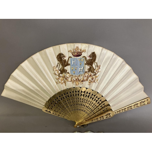 32 - Two mid-19th century fans, the first with carved and pierced wood sticks, painted in gold, the cream... 