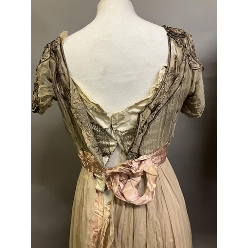 329 - An Edwardian evening dress in dark cream chiffon, with short sleeves and scoop neck, lined in silk, ... 