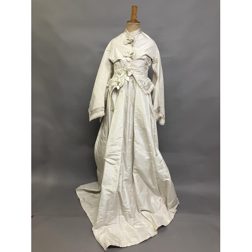 334 - A mid-1860’s two-piece wedding ensemble, cream silk, the tailored bodice with bell sleeves, the slee... 