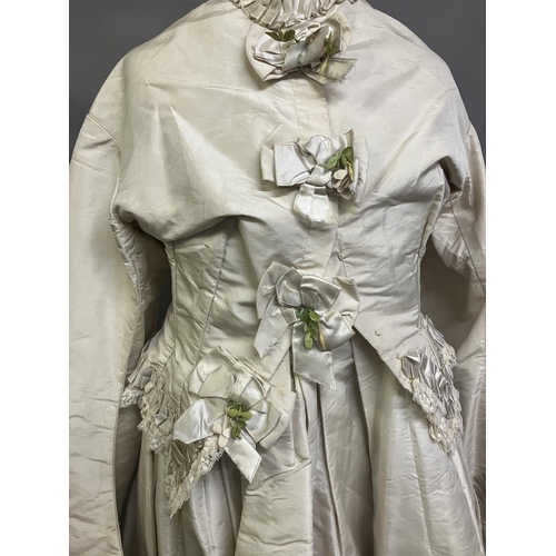 334 - A mid-1860’s two-piece wedding ensemble, cream silk, the tailored bodice with bell sleeves, the slee... 