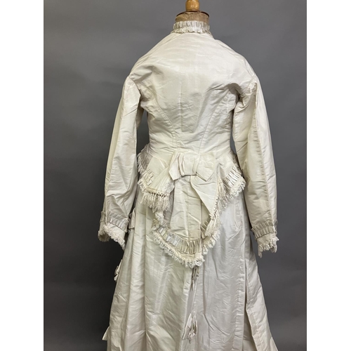 334 - A mid-1860’s two-piece wedding ensemble, cream silk, the tailored bodice with bell sleeves, the slee... 