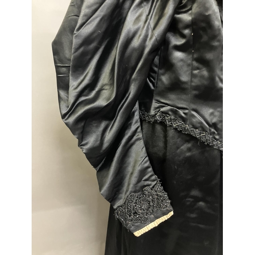 340 - C 1895/1900, a two piece black silk satin skirt and boned bodice bearing the attribution, in gold on... 