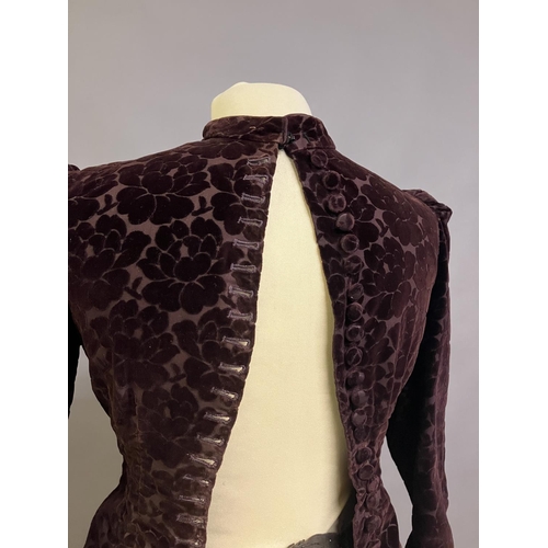 344 - An 1880’s cut velvet two piece in ruby, the tailored jacket boned and lined in patterned cotton, the... 