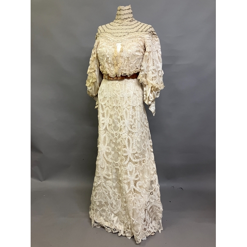 322 - An Edwardian tapelace wedding ensemble, the high-necked bodice in ivory silk satin, trimmed with cre... 