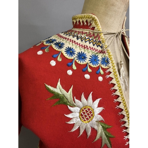 184 - A Child’s folk dress coat, in red wool with cream cuffs, seam and collar, heavily embroidered with f... 