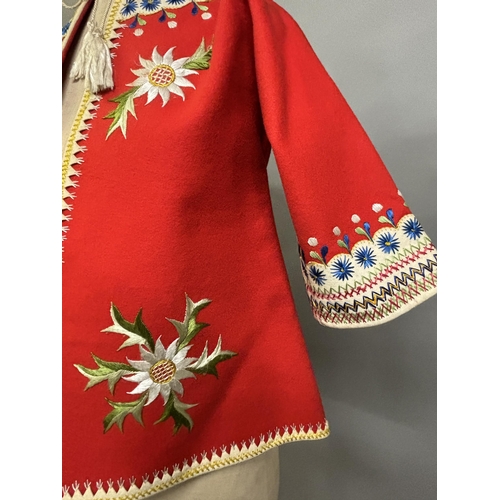 184 - A Child’s folk dress coat, in red wool with cream cuffs, seam and collar, heavily embroidered with f... 