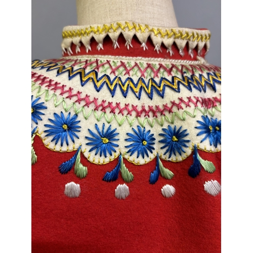 184 - A Child’s folk dress coat, in red wool with cream cuffs, seam and collar, heavily embroidered with f... 