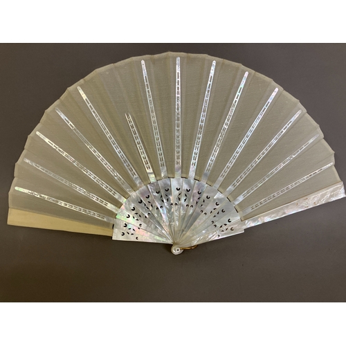 49B - A white Mother of Pearl fan, with a hint of colour, the guards and gorge with decorative piercing an... 