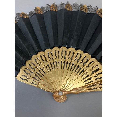 17 - A wood fan, the monture carved and pierced, painted gold, c 1870’s, the black silk satin leaf with b... 