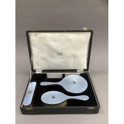 373 - A silver and blue enamel three piece dressing table set, in fitted case, comprising hand mirror, hai... 