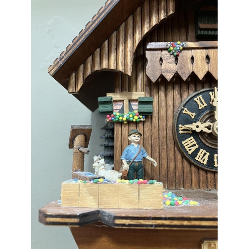 325 - A Black Forest style cuckoo clock with swinging pendulum and weights having two figures , goats and ... 