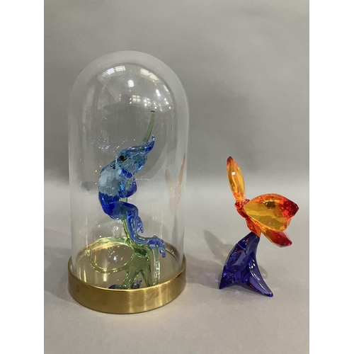 44 - A Swarovski crystal blue frog on branch in glass dome together with an orange butterfly on purple fl... 